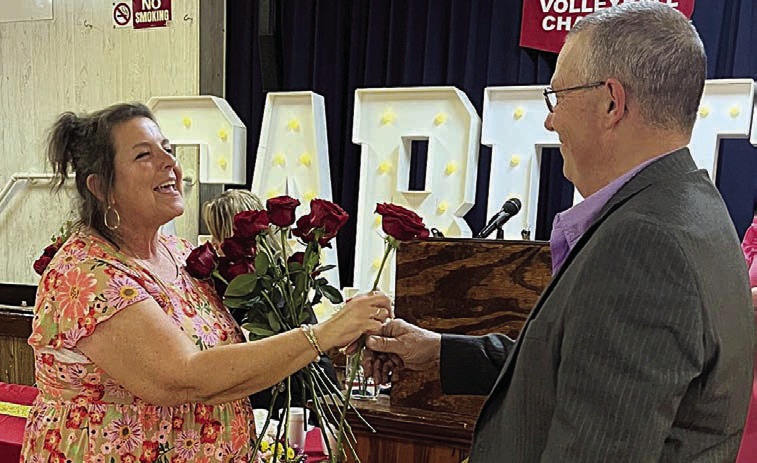 Donna Kunz (left) receives the last of 40 roses representing her 40 years at St. Rose from her husband, Darren.