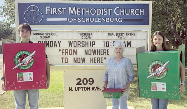 Samaritan’s Purse “Operation Christmas Child” boxes are being held by (from left) Nick Rorschach, Margie Gresham and Molly Rorschach in front of the First Methodist Church of Schulenburg sign. The project solicits shoeboxes filled with items to be distributed to children around the world.