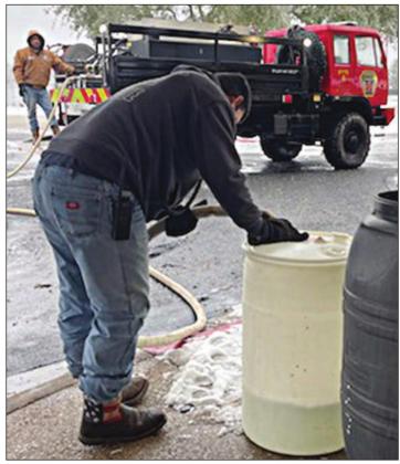 Schulenburg Volunteer Fire Department firefighters Gary Eudy (foreground) and Johnny Guerrero use Brush 4 to fill up barrels with water at Monument Hill Nursing Center last week.