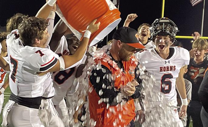 Three Shorthorn players successfully execute a sneak attack on head coach Luke Hobbs to give him an ice shower in celebration of their bi-district win last Friday in New Braunfels. Sticker Photo By Darrell Vyvjala