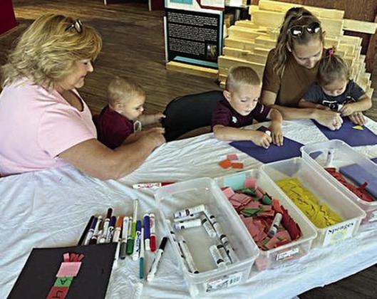 Arts and craf ts projects were set up for all to enjoy. At the station pictured above, children wrote the letters of a name on colored squares and then arranged them in order to create a rocket ship.