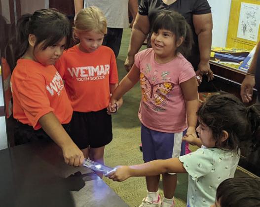 An electricity conduction experiment using an energy stick from Steve Spangler Science is being performed by the four girls holding hands in the circle. The experiment demonstrates how energy can flow through the human body.