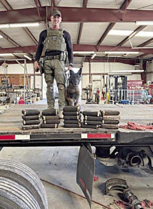 Sgt. Randy Thumann and K-9 partner, Kolt, are shown on the trailer bed with the 23 kilos of cocaine they discovered hidden in its axles.