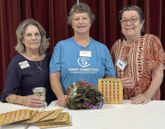Bingo – Anne Frye (left) of First Texas Home Health holds a jar of cookies given as thanks for calling the bingo game in Weimar. Janeice Collins (center), a valued volunteer, holds her prize from the blackout game. Donna King (right) made the crocheted blanket.