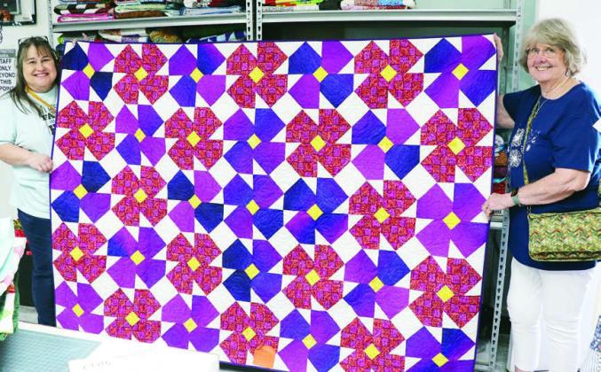 One of the “Poppy Quilts” constructed by the Colorado Valley Quilt Guild for the “Hugs for the Hill Country” drive to aid flood victims is being displayed by Connie Kortz (left) of Victoria and Kathy Theut (right) of CVQG.