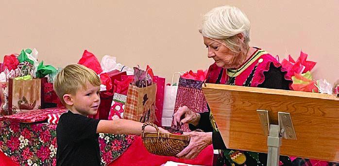 During the white elephant gift exchange, Dominik Woodworth (left) performs the drawing for who is next to choose a gift as Betty Danner holds the basket.