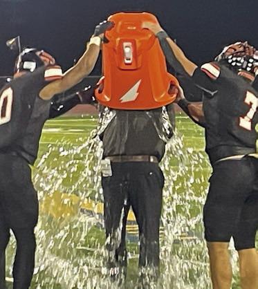 Jakele Houston (left) and Landon Conner (right) douse head coach Clay Ferguson to celebrate the playoff win. Sticker Photo By Darrell Vyvjala