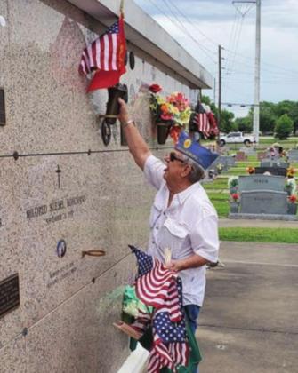 Robert Hranicky places a flag at the mausoleum in the St. Rose Cemetery.