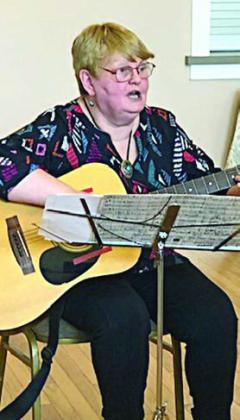 Guest speaker author Barbara Ortwein singing and playing the guitar. She also spoke about her book.