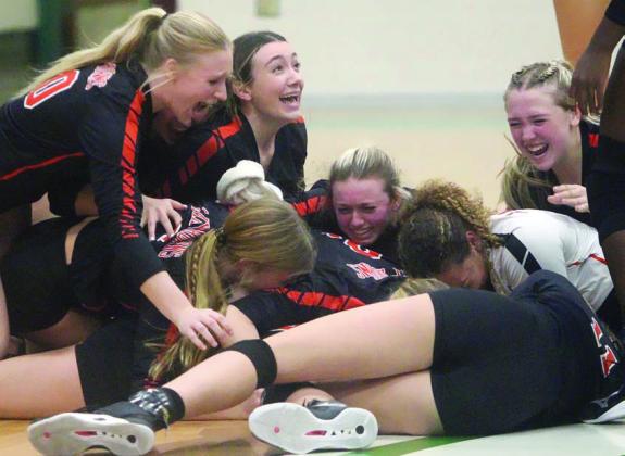 Lady Horn players go to the floor in jubilation following the final point of the regional championship match on Saturday afternoon at Brenham High School. Sticker Photo By Darrell Vyvjala