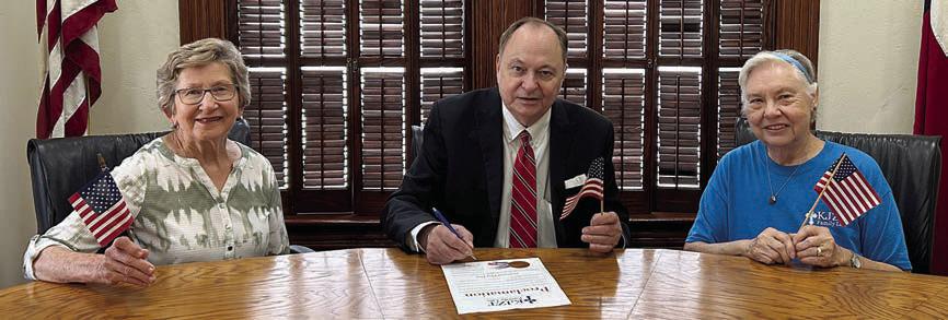 KJZT Family Life representatives Helen Faldyn (left) and Lillian Kallus (right) were on hand as Fayette County Judge Dan Mueller (center) signed a proclamation declaring June 14 as National Flag Day.