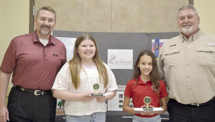 POSTER CONTEST winners in Division 2 (grades 3-6) were Emma McCourt (second from left) of St. Rose of Lima Catholic School in Schulenburg and Sophie Janda (second from right) of Sacred Heart School in La Grange. Award sponsors were National Bank &amp;amp; Trust, represented by Scott McManus (left), and Fayette Savings Bank, represented by Mark Friedrich (right).