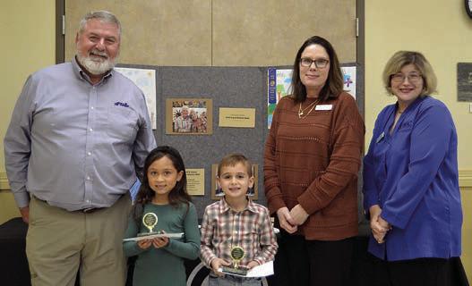POSTER CONTEST winners in Divisio n 1 (grades K-2) were Aurora Galvez (second from left) and Jack Wied (third from left), both students at Sacred Heart School in La Grange. Presenters were Mark Friedrich (left) of Fayette Savings Bank and Tracy Denton (second from right) and Jessica Montez (right) both representing Fayette Electric Cooperative.