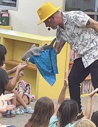 Mr. Leo’s shark puppet snacks on a youngster’s finger during last Friday’s show at the library. Sticker Photo By Darrell Vyvjala