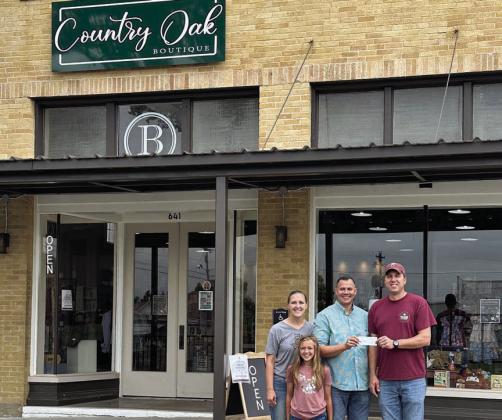 Schulenburg Economic Development Corporation President Paddy Magliolo (right) presents a $7,500 grant to Kevin, Megan, and Hannah Bartos. Bartos Investments, LLC applied for the beautification grant for the Bartos’ recently-opened business, Country Oak Boutique, at the corner of North Main Street and Wolters Avenue.
