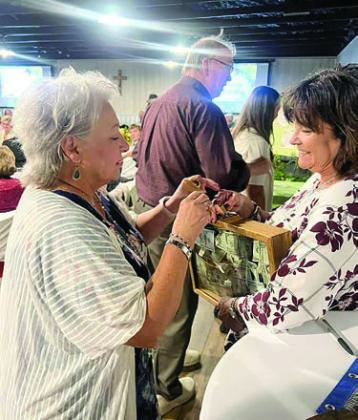 GAME – Barbara Mache (left), who was seated at the table purchased by Queen of the Holy Rosary Church in Hostyn, tries to see if her key will be the winner in the Unlock the Loot game for $1,000.