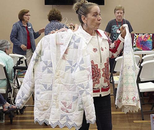 The “Re-Imagined Fash ion” program showed how old quilts can be made into jackets. Speaker Patricia Roebuck holds two jackets as examples.