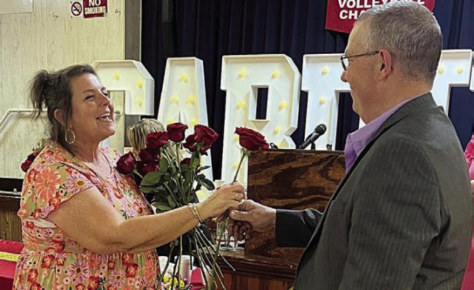 Donna Kunz (left) receives the last of 40 roses representing her 40 years at St. Rose from her husband, Darren.