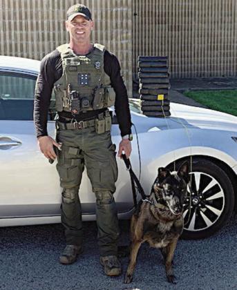 Sgt. Randy Thumann and Kolt pose in front of the Nissan Altima and the packages of cocaine they found after a traffic stop.