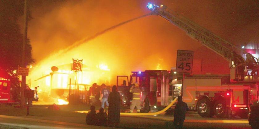 The SVFD’s ladder truck sends down a heavy stream of water to help get Tuesday morning’s structure fire under control while the Juarez family (center, in the foreground) watch helplessly as their house burns to the ground. Sticker Photo By Darrell Vyvjala