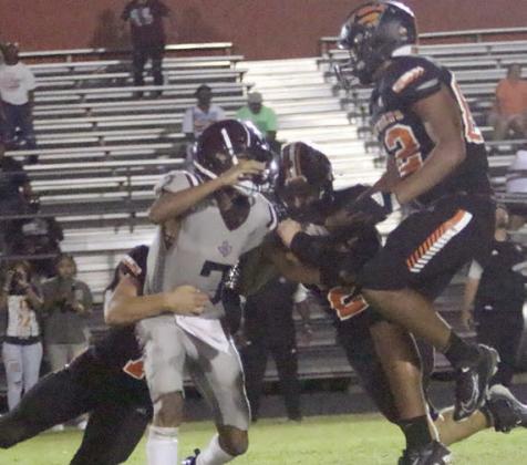 Bryce Stoever gets to the Hearne quarterback in the fourth quarter along with John Davis (middle) and Jayvan Luhrs. Sticker Photo By Layne Vyvjala
