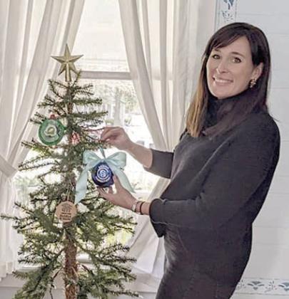 Amanda Kridel, director of marketing and development for Senior Connections, puts the ornament she made on the Stanzel Museum’s Christmas tree.