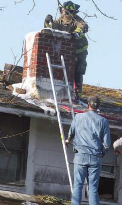 SVFD firefighter Travis Leihardt uses a foam and water mixture to contain Thursday’s chimney fire. Assisting is fellow SVFD member John Schindler. Sticker Photo By Darrell Vyvjala