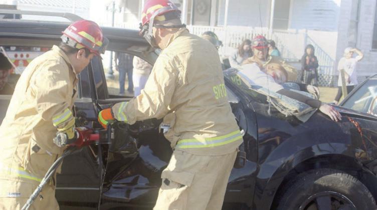 Firefighters use extrication tools to remove the door of the vehicle from which Katry Kobza was ejected through the windshield and later pronounced “deceased.” Sticker Photo By Darrell Vyvjala