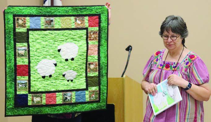 LEFT PHOTO – Sandy Courrier shows her quilt constructed to accompany the children’s book Cheepy and Grandma Mare.