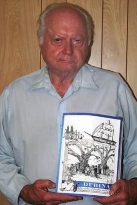 Ed Janecka shows off his book on the history of Dubina. Sticker Photo By Darrell Vyvjala