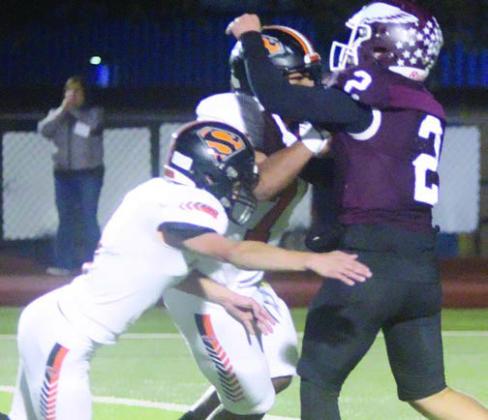 Adin Beyer (left) and Jayvan Luhrs pressure Eagle quarterback Mc-Cray Jacobs in the first quarter. Sticker Photo By Darrell Vyvjala