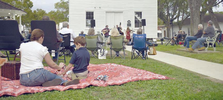 Arts for Rural Texas hosts a free live music series every March and October in Fayetteville on the historic courthouse lawn. Performers from a past series are shown in front of the courthouse while attendees with lawn chairs and picnic blankets enjoy the music.