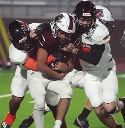 Keisean Johnson (left) and Kenny Schramek tackle Daniel Pena for a loss in the fourth quarter. Sticker Photo By Layne Vyvjala