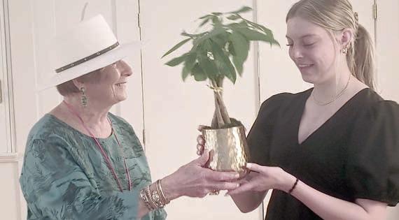 Scholarship recipient Kaylee Beyer (right) received a braided Money Tree plant from Nova Stonecipher (left).