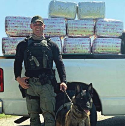 Sgt. Randy Thumann and his K-9 partner, Kolt, with the 253 pounds of marijuana they discovered Monday.