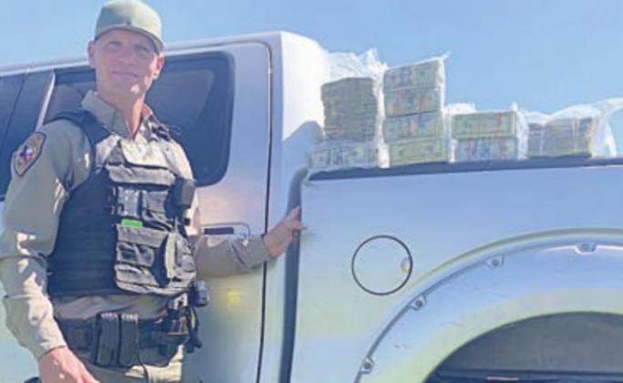 Interdiction Investigator David Smith stands next to $136,000 in U.S. currency confiscated during a moneylaundering arrest.