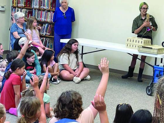 Youngsters eagerly raise their hands to ask questions about the bearded dragon, seen on the shoulder of Desiray Almaraz. Sticker Photo By Darrell Vyvjala