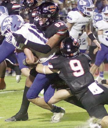 Emerson Harvey (No. 9) and Jayvan Luhrs team up to drop Trent Sevcik for a loss of 1 in the second quarter. Sticker Photo By Layne Vyvjala