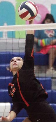 Grace Schramek knocks an attack over the net in the first set. Sticker Photo By Darrell Vyvjala
