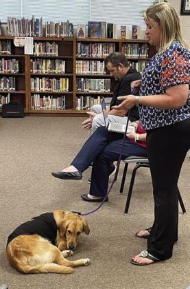 Counselor Heather Pavlu (right) introduces therapy dog “Birdie” to the school board during Monday night’s meeting. Sticker Photo By Darrell Vyvjala