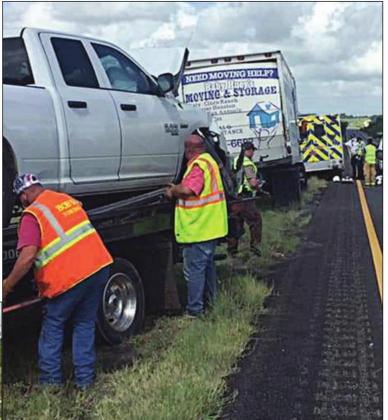 Above: The Dodge pickup gets loaded on a wrecker following the accident that claimed the life of a Flatonia man after he crashed into the rear of a moving van (shown in background).