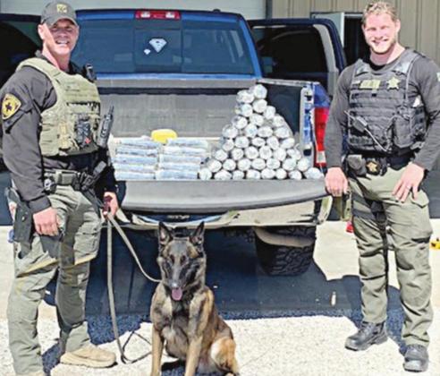 Sgt. Randy Thumann, his K-9 partner Kolt and Deputy Jeremy Ellison with $7.3 million in meth and cocaine confiscated during a traffic stop on I-10 near Schulenburg.