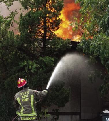 Schulenburg VFD First Assistant Chief Drew Brossmann directs a stream of water to the western corner of the building.  Photo By Melanie Berger / Courtesy of Flatonia Argus