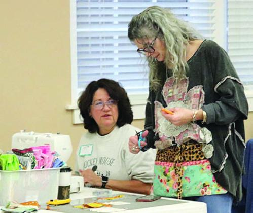 Cutting a strip for Lisa Sandlin (left) is Michelle Lavender (right).