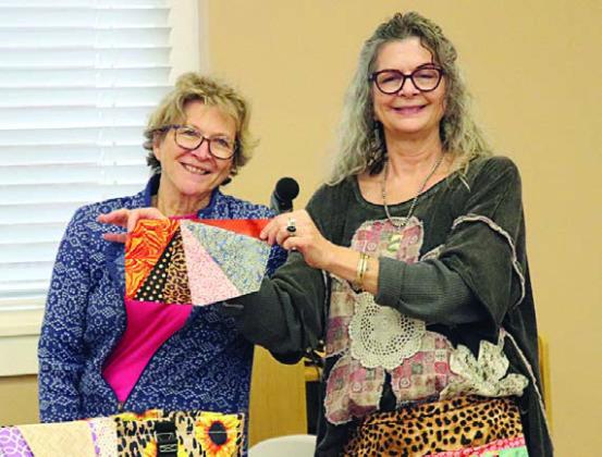 A “Wonky Triangle” created by Tricia Griste (left) is being held up by Michelle Lavender (right).