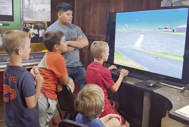 Volunteer Zuriel Robles (third from left) guides the co-pilots on the Real Flight Simulator.