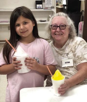 A special treat was enjoyed by members in Schulenburg on July 3. HEB sponsored a Fourth of July hot dog meal,  followed by snow cones sponsored by the City of Schulenburg and Mayor Connie Koopmann. . Shown with one of the youngsters from the Boys &amp; Girls Club is Kitra Ruiz.