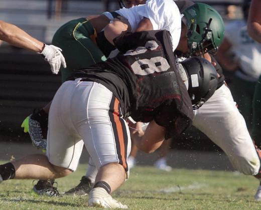 Marshall Wellborn leads to the charge in stopping an Eagle runner early in the scrimmage. Sticker Photo By Darrell Vyvjala