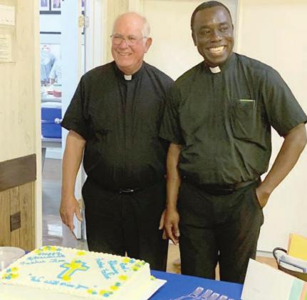 The Rev. Timothy Kosler (left) and the Rev. Felix Twumasi are shown with the cake the was part of their farewell party last week at the K. of C. Hall. Sticker Photo By Bernadette Gillings
