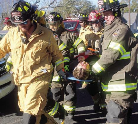 SVFD personnel assist EMS in carrying one of the injured teens to the ambulance for transport to the hospital. Sticker Photo By Darrell Vyvjala